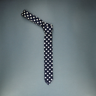 Недорогой узкий мужской галстук синего цвета с узором в виде звезд.